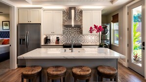 Een moderne keuken met een groot kookeiland, roestvrijstalen apparatuur en een decoratieve spatwand.