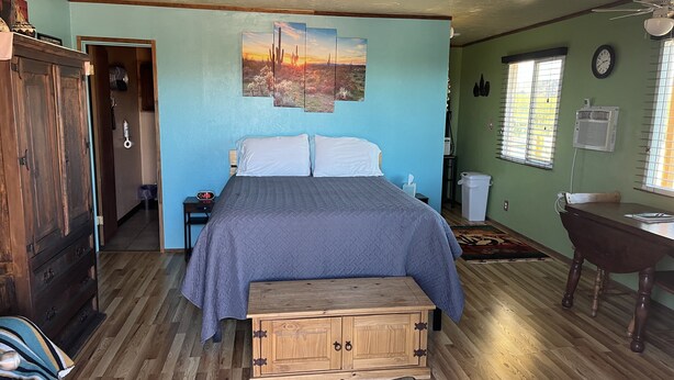A bedroom with a bed, a wooden cabinet, a desk, and a painting on the wall. - Casita with Mountain View (Congress)
