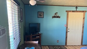 A room with a wooden dining table, a television, a ceiling fan, and a door. - Casita with Mountain View (Congress)