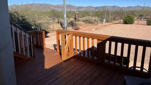 A wooden deck with a metal railing overlooking a desert landscape with mountains. - Casita with Mountain View (Congress)