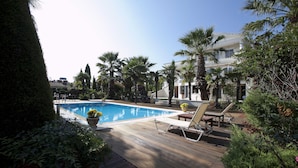 A swimming pool with lounge chairs, surrounded by palm trees and potted plants. - Villa Elena Perea Thessaloniki (Perea Thessaloniki)