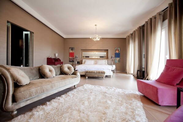 A bedroom with a bed, a sofa, a chair, and a large fluffy rug. - Villa Elena Perea Thessaloniki (Perea Thessaloniki)