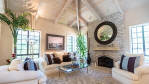 A spacious living room with a high ceiling, a fireplace, and a large window. - A Writer's Hideaway and Private Escape for the Hollywood Elite. (Westlake Village)