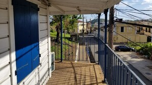 Une véranda couverte donnant sur une rue et des immeubles.