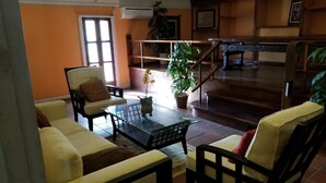 Un salon comprenant un canapé, des fauteuils, une table basse et un escalier.