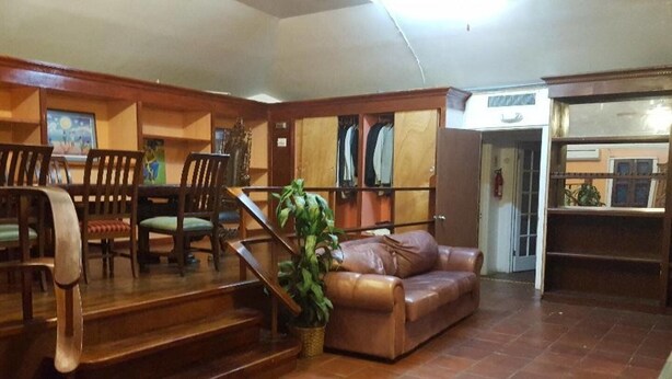Un vaste espace de vie comprenant un escalier, un canapé en cuir, des meubles en bois et une plante en pot.