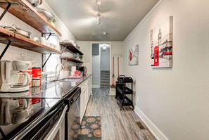 A kitchen with a black countertop, wooden shelves, and a coffee maker. - Indie Escape-2 in 1- stone’s throw to the Plaza (Oklahoma City)