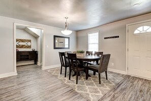 A dining area with a round table, chairs, a rug, a ceiling light, and a door. - Indie Escape-2 in 1- stone’s throw to the Plaza (Oklahoma City)