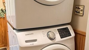 A stacked washer and dryer unit with a control panel and a wall-mounted electrical outlet. - Quaint cottage in the Smoky Mountain area convenient to all the attractions (Kodak)