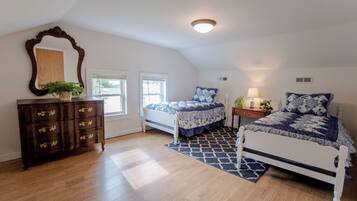 Une chambre avec deux lits, une commode, un miroir et une fenêtre.
