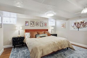 Un dormitorio con una cama grande, dos mesitas de noche, una lámpara en el techo y obras de arte en las paredes.