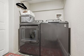 A compact, stainless steel laundry machine with a front-loading door, a small control panel, and a drying rack on top.