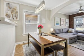 Una sala moderna con una mesa de comedor de madera, un sofá gris y una araña.