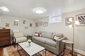 Una sala de estar con sofá, sillón, mesa de centro y lámpara de pie.