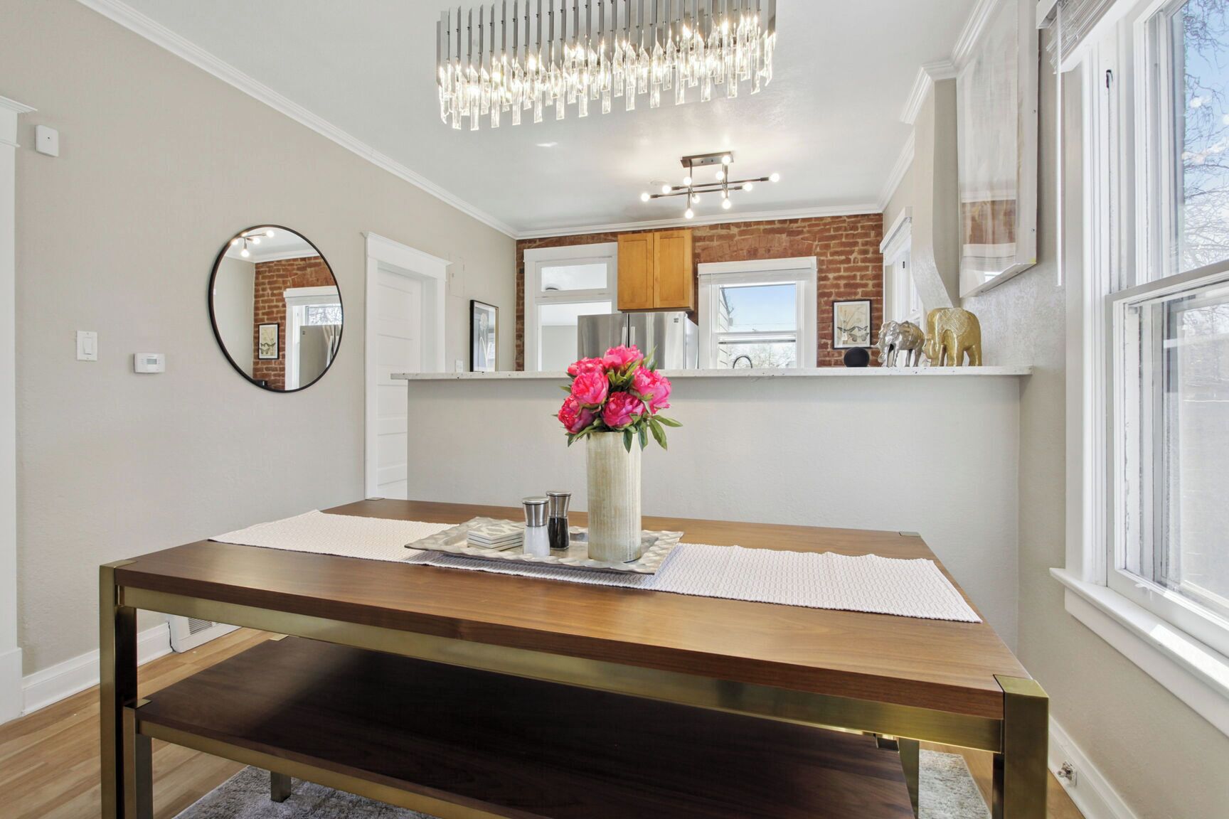 A dining area with a wooden table, a vase with flowers, and a chandelier.