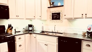 A kitchen with white cabinets, a black stove, and a coffee maker. - Modern Farmhouse near VMI, W&L, SVU & VA Horse Ctr (Lexington)