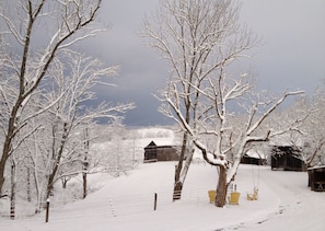 Escape to a serene winter wonderland surrounded by snow-covered trees and a charming barn.