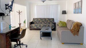 Un salon comprenant un bureau, un canapé, une table basse et un ventilateur de plafond.