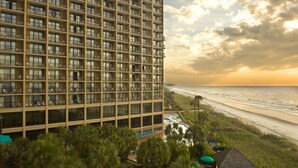 Ein Hochhaus-Hotel mit zahlreichen Balkonen mit Blick auf einen Strand.