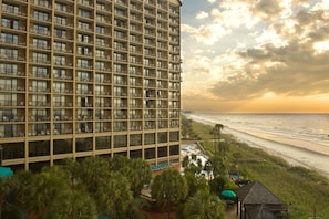 Un hotel moderno de altura con varios balcones que dan a una playa.