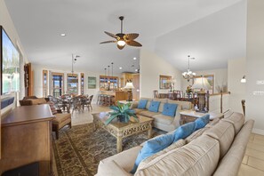 A spacious living room with a large sofa, a coffee table, and a dining area with chairs and a table.