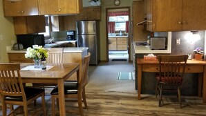 Una cocina compacta con armarios de madera, un refrigerador de acero inoxidable y una zona de comedor con mesa y sillas de madera.