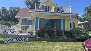 A two-story house with a balcony, a fenced deck, and a red car parked in front. - The Great Escape Sleeps 10 Comfortably (6 beds)  & Awesome Lake Views!  (Clear Lake)