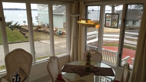 A cozy room with wicker chairs and a glass table, large windows with a view of a lake and a cottage sign. - The Great Escape Sleeps 10 Comfortably (6 beds)  & Awesome Lake Views!  (Clear Lake)
