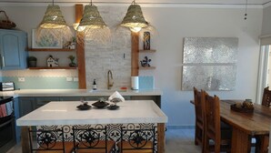 A modern kitchen with a central island, pendant lights, and a dining area with wooden chairs. - Costa Azul Oceanfront Condo w/Views, Surf, Swimmable Beach (San Jose del Cabo)