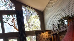 Una sala de estar acogedora con chimenea, un ventanal con vistas a un árbol y un sofá confortable.