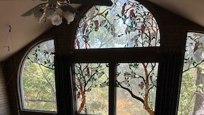 Una habitación con un amplio ventanal de arco, una escalera de madera y vistas a una terraza.