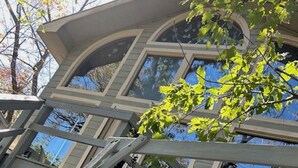 Una casa con un diseño arquitectónico único, que presenta una escalera en espiral y ventanas amplias.