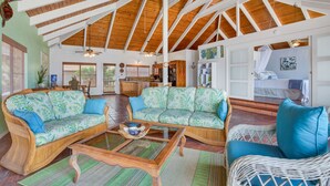 A spacious living area with high ceilings and wooden beams, featuring two sofas with patterned upholstery and a glass coffee table. - AS SEEN ON HGTV BEACH HUNTERS! Oceanfront, Amazing Whale Watching and Snorkeling (Captain Cook)