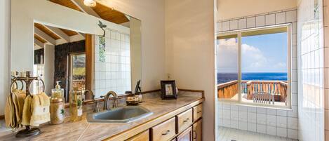 A kitchen with a large window overlooking a balcony with a view of the ocean.