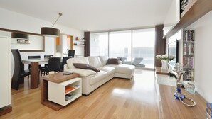 A modern living room with a white sofa, a wooden coffee table, and a bookshelf.