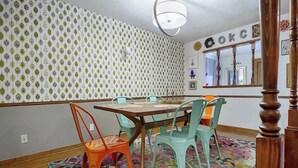 A dining area with a wooden table and colorful chairs, patterned wallpaper, and a mirror reflecting the room. - Eccentric Escape-hop, skip, jump to Plaza District (Oklahoma City)