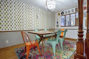 A dining area with a wooden table and colorful chairs, patterned wallpaper, and a mirror reflecting the room. - Eccentric Escape-hop, skip, jump to Plaza District (Oklahoma City)