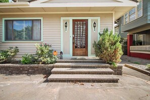 A two-story house with a front porch, a wooden door with a window, and a brick pathway leading to the entrance. - Eccentric Escape-hop, skip, jump to Plaza District (Oklahoma City)