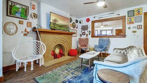 A cozy living room with a fireplace, comfortable seating, and various wall decorations. - Eccentric Escape-hop, skip, jump to Plaza District (Oklahoma City)