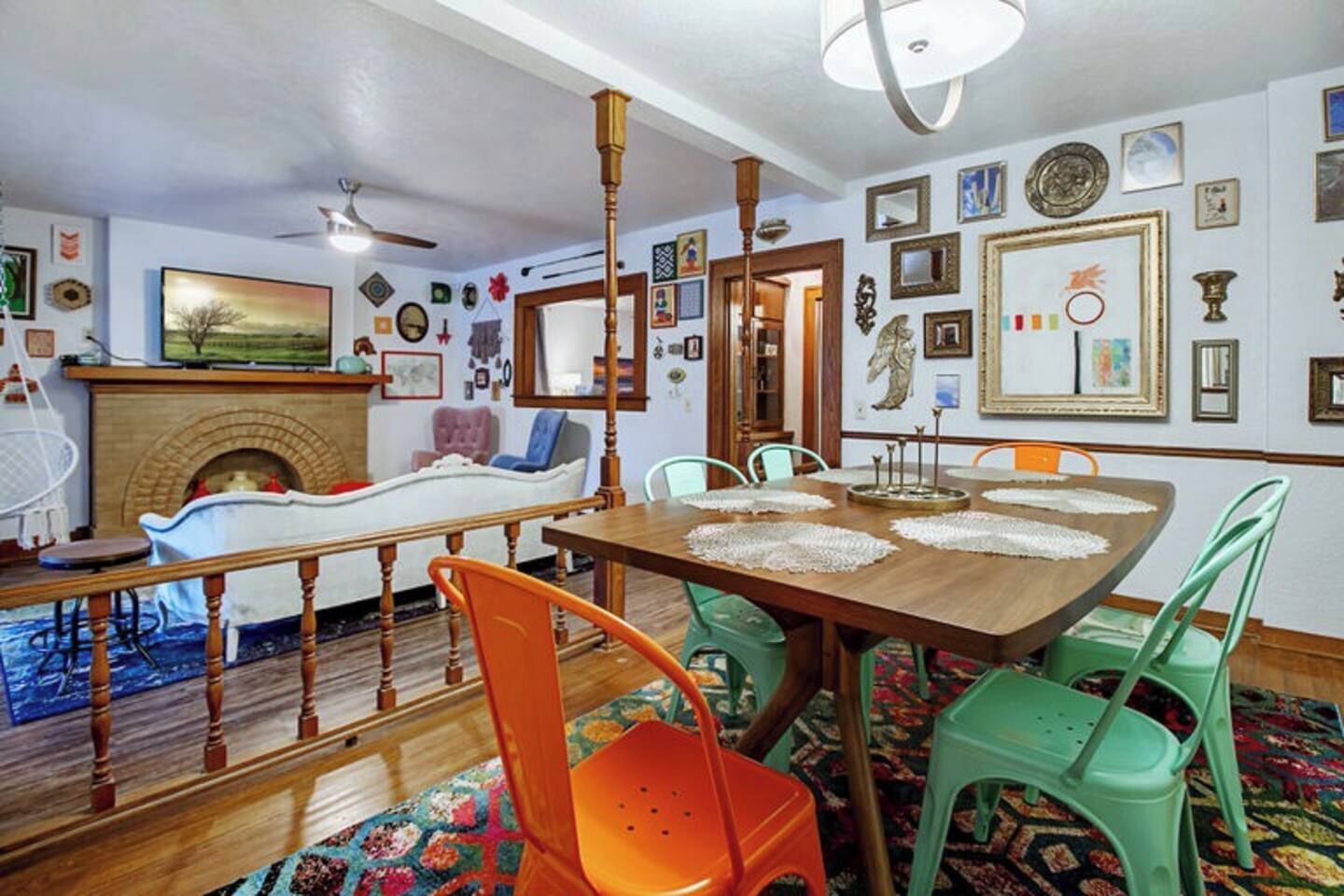 A dining area with a wooden table, green and orange chairs, and a fireplace.