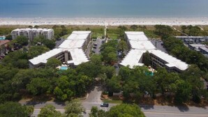 An aerial view of a coastal hotel with multiple buildings, a parking lot, and a beach in the background. - Seabatical-Beautiful ocean view! w/new bikes & Chairs (Hilton Head Island)