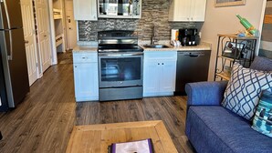 A modern kitchen with white cabinets, stainless steel appliances, and a stone backsplash. - Seabatical-Beautiful ocean view! w/new bikes & Chairs (Hilton Head Island)