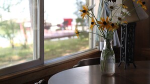 A table with a vase of flowers and a lamp, near a window with curtains.