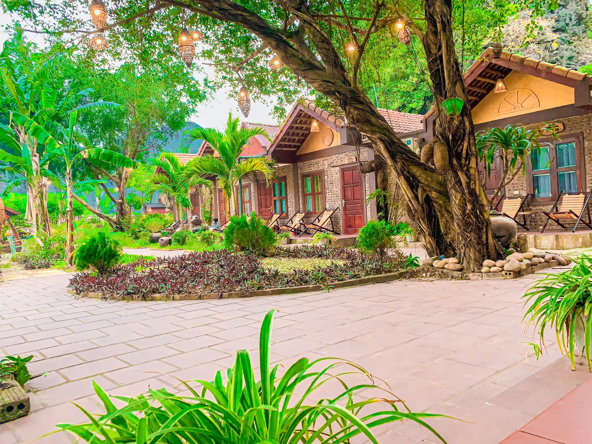 A traditional-style building with a courtyard, surrounded by lush greenery and trees.