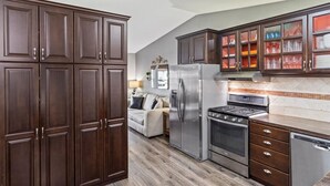 A modern kitchen with dark wood cabinets, stainless steel appliances, and a tiled backsplash. - Hot Tub Gameroom Great Location Sparkling Clean (West Valley City)