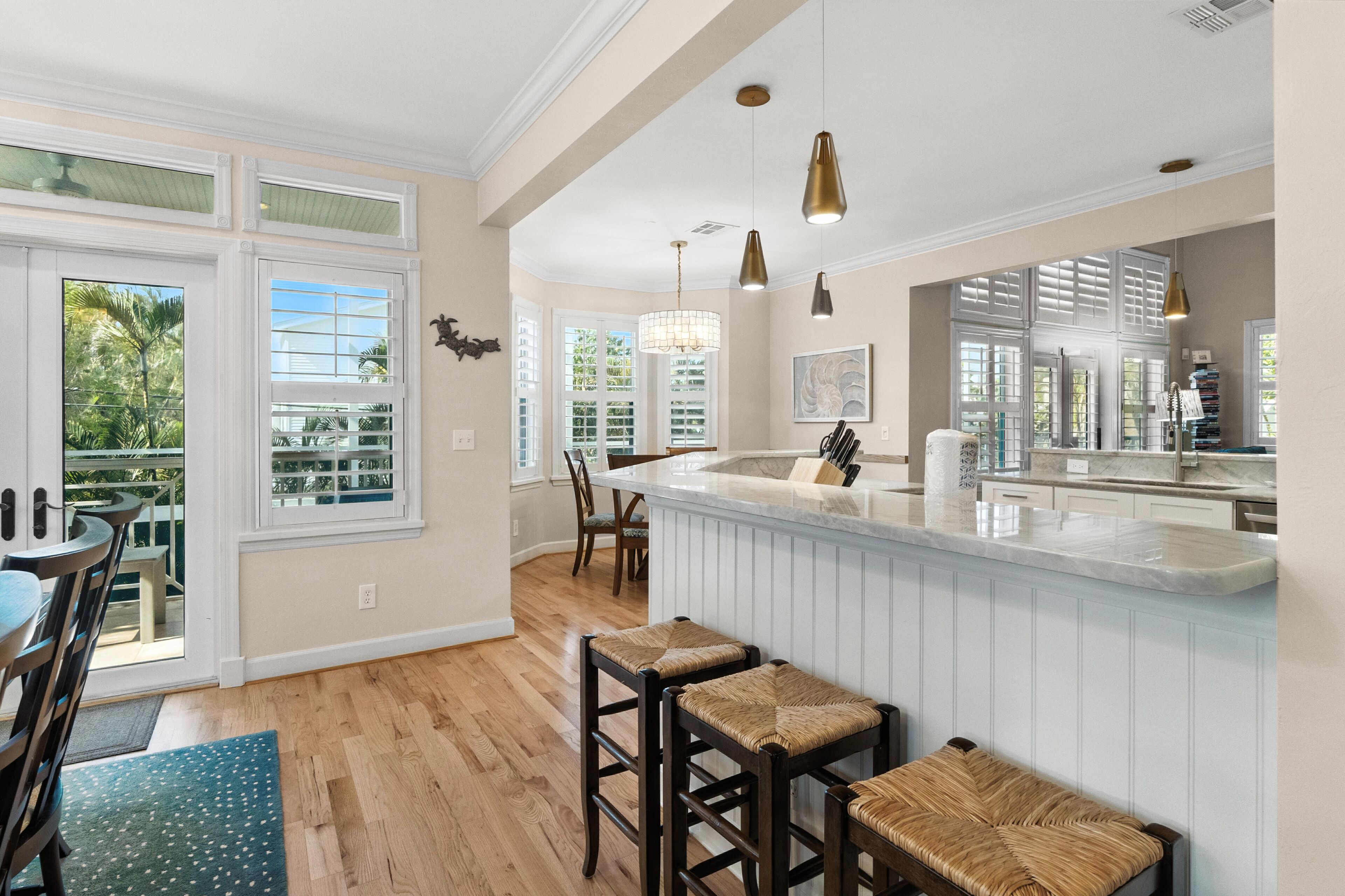 A kitchen with a large island, bar stools, and pendant lighting.