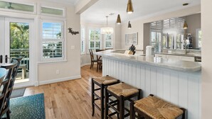 A kitchen with a large island, bar stools, and pendant lighting. - 5-bedroom vacation home in the Village with just a short walk to Captiva Beach! (Captiva)