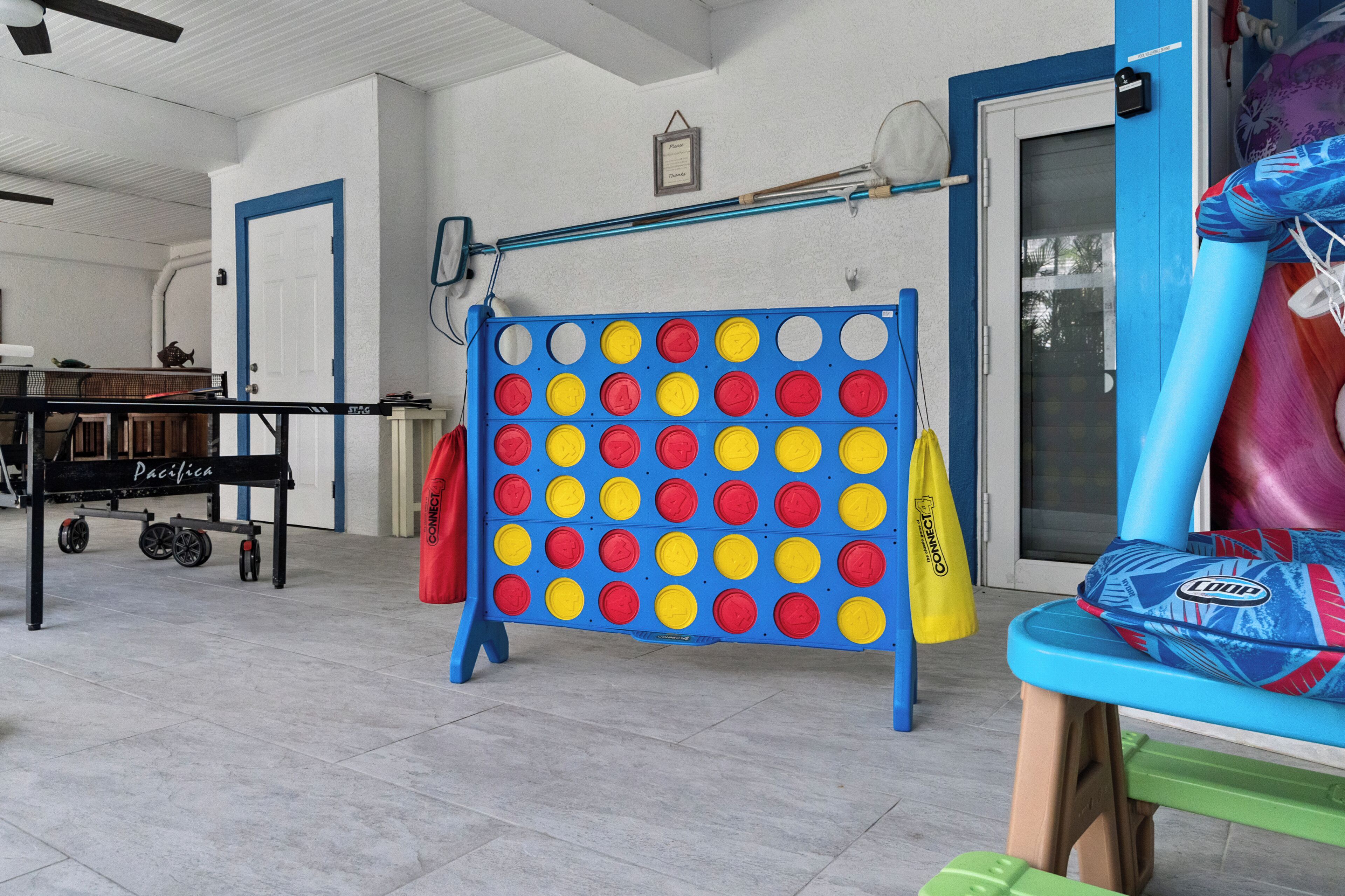 A room with a blue and yellow game board, a table with a 'Pacific' sign, and a colorful slide.