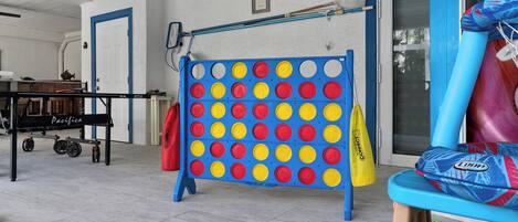 A room with a blue and yellow game board, a table with a 'Pacific' sign, and a colorful slide.