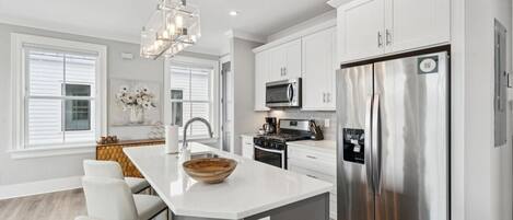 Una cocina moderna con armarios blancos, electrodomésticos de acero inoxidable y una isla central con asientos.